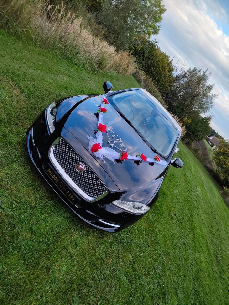Tył czarnego Jaguara z tablicą Młoda Para